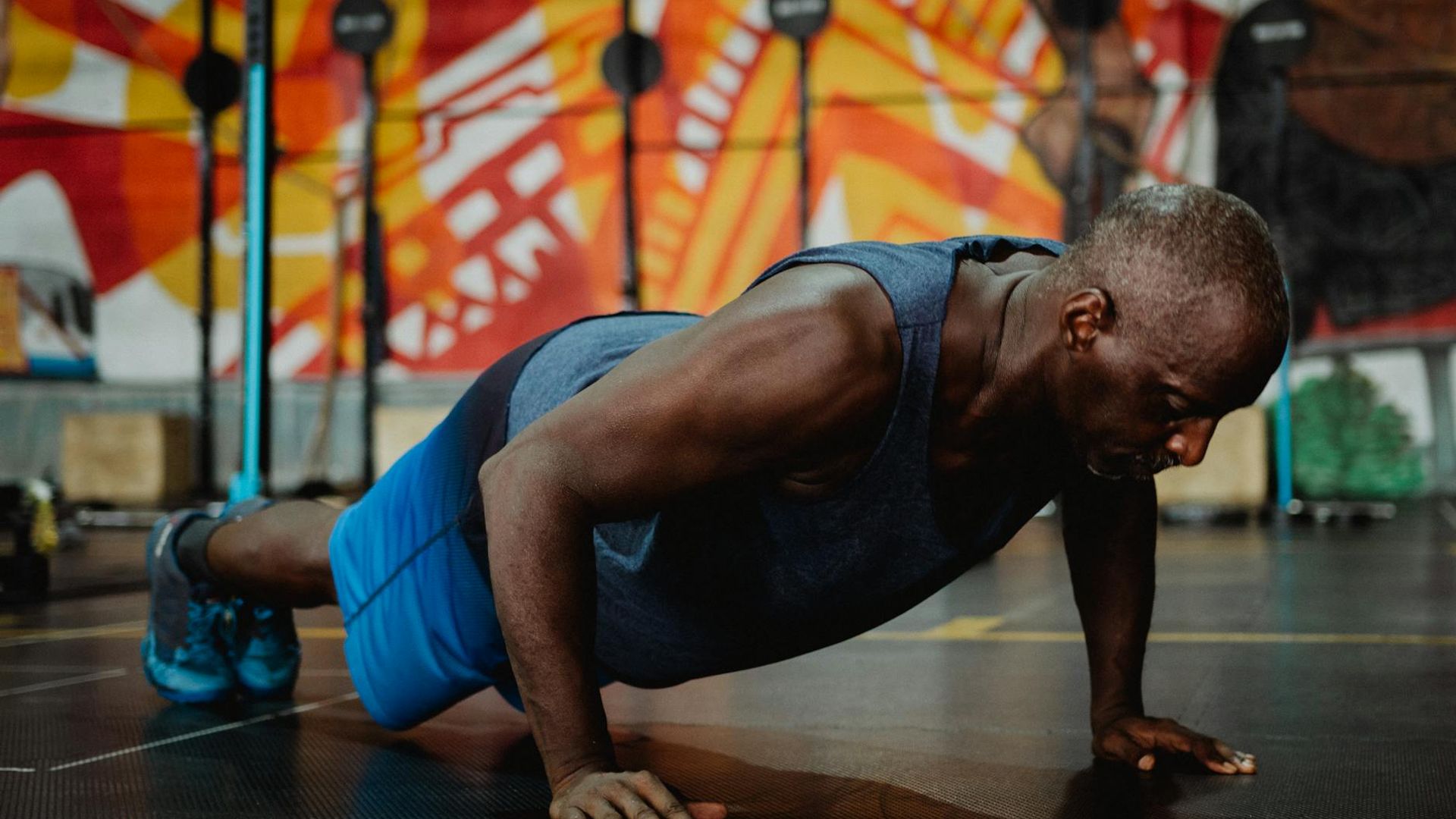 Athletic man performing strength exercises in a dark gym environment